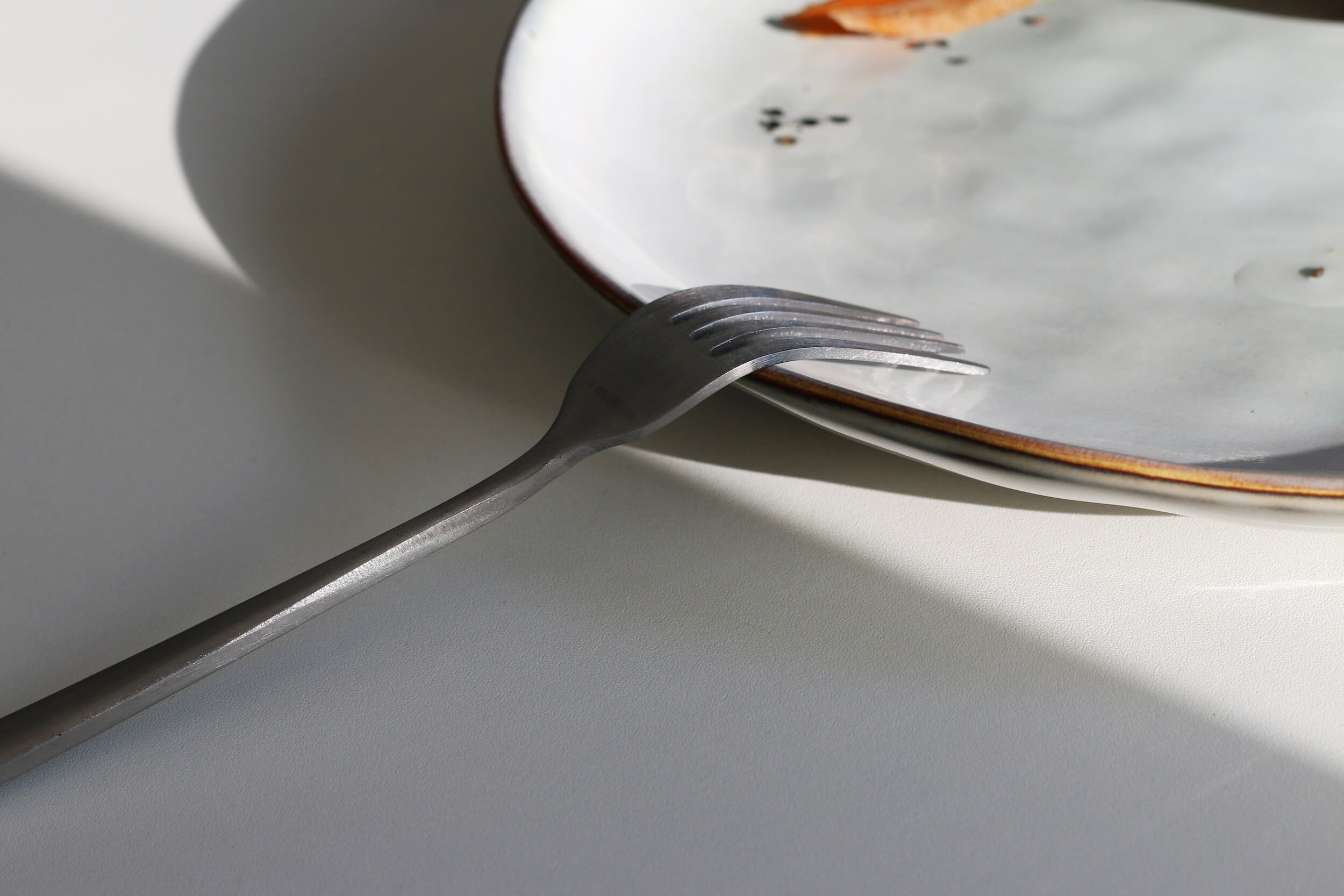 TAKINOA photo shoot of fork balanced on a ceramic plate with light and shadow symbolizing TAKINOA inspiring change